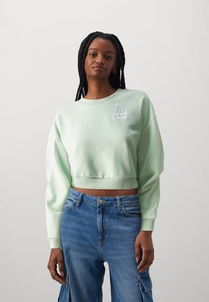 Sudadera corta de color verde menta con cuello redondo y logotipo bordado de "LA" en el pecho. Presenta mangas anchas y dobladillo acanalado.