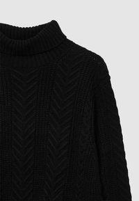 Schwarzer gestrickter Pullover mit hohem, geripptem Kragen. Verfügt über ein strukturiertes Chevron-Muster und grobes, warmes Gewebe.