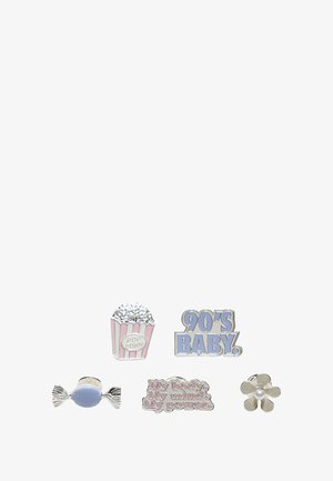 Sada pěti smaltových pinů: kyblíček popcornu, text "Dítě 90. let", modrý bonbón, motivační citát a stříbrná květina, s různými barvami a designy.