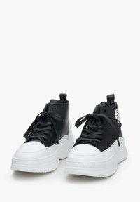 Zwarte high-top sneakers met witte rubberen zolen, textuurleer, ronde neus en platte veters, met een logo-detail aan de zijkant.