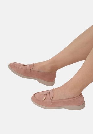 Mocasines de ante rosa con suela beige plana, que presentan un detalle de lazo decorativo y costuras sutiles a lo largo de los bordes.