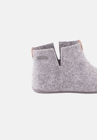 Chaussure slip-on en feutre gris clair avec une ouverture en V, petit talon, semelle en caoutchouc et une petite étiquette de marque en métal "SHEPHERD" sur le côté.