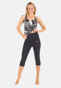 Svarta cropped leggings med hög midja. Tryckt ärmlös topp med vit text och grafiska mönster. Slät, stretchig kvalitet.