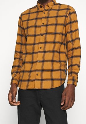 Chemise à manches longues à carreaux en moutarde et bleu marine, avec fermeture à boutons, un col classique et un tissu doux et texturé.