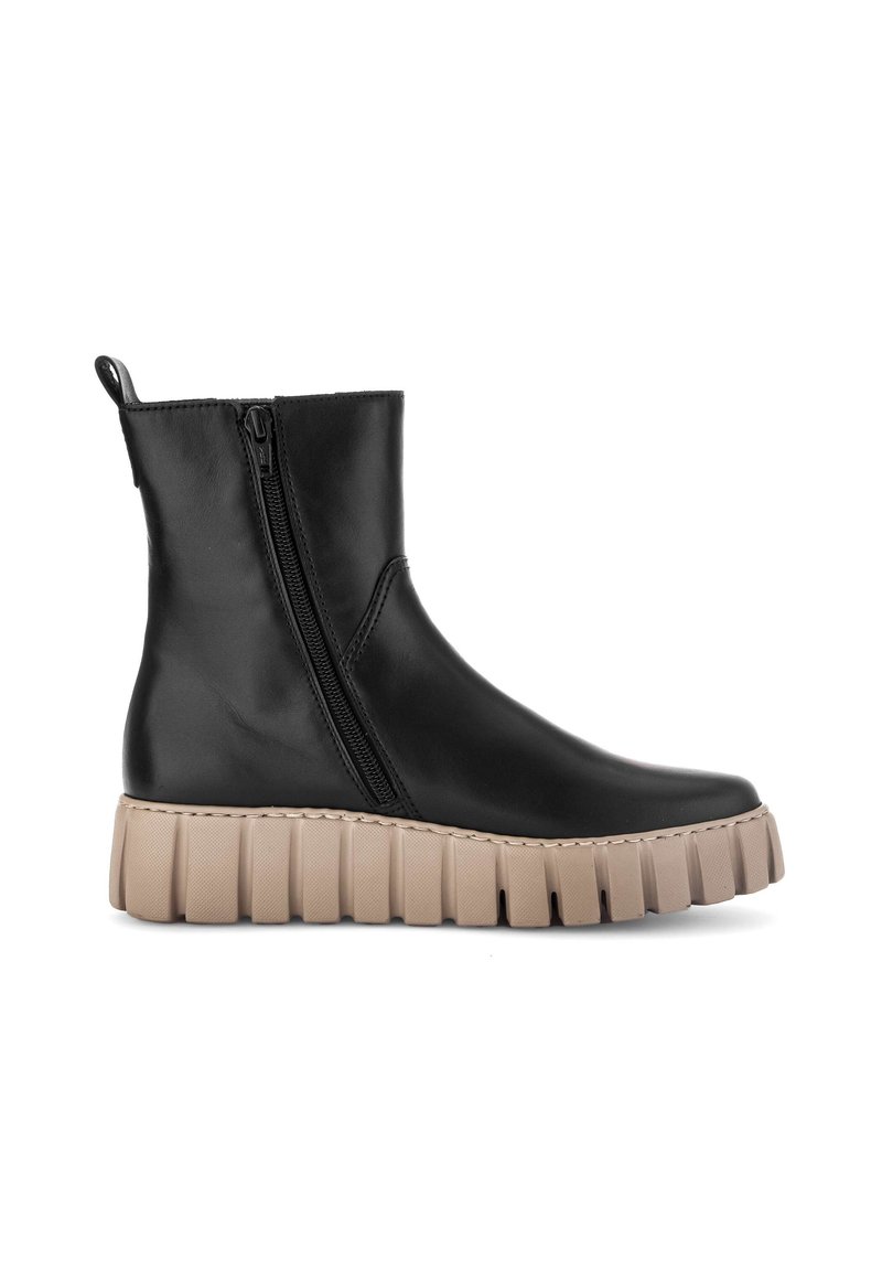 Bottine en cuir noir avec semelle épaisse beige à relief et fermeture éclair sur le côté, isolée sur fond blanc.