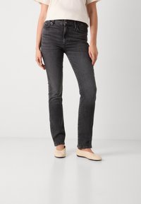 Donker gewassen skinny jeans met een hoge taille, voorzien van vijf zakken en subtiele stiksels. Gecombineerd met lichtbeige ballerina's.