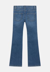 Μπλε τζιν τζιν με επίπεδη διάταξη, εμφανίζοντας την πίσω πλευρά με δύο πίσω τσέπες και θηλιές για ζώνη, με ελαφρώς φαρδιά κοπή στα μπατζάκια.