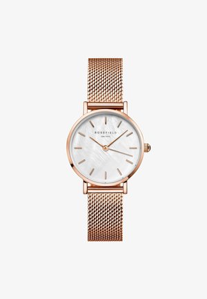 Montre avec un bracelet en maille rose doré, dotée d'un cadran rond en nacre blanche, marquage horaire minimaliste et d'une couronne simple pour le réglage.