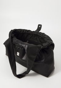 Zwarte leren tas met een zachte, gathers bovenkant, lange hengsels en een klein metalen logo aan de buitenkant. Bevat een binnenvak met rits voor opbergruimte.