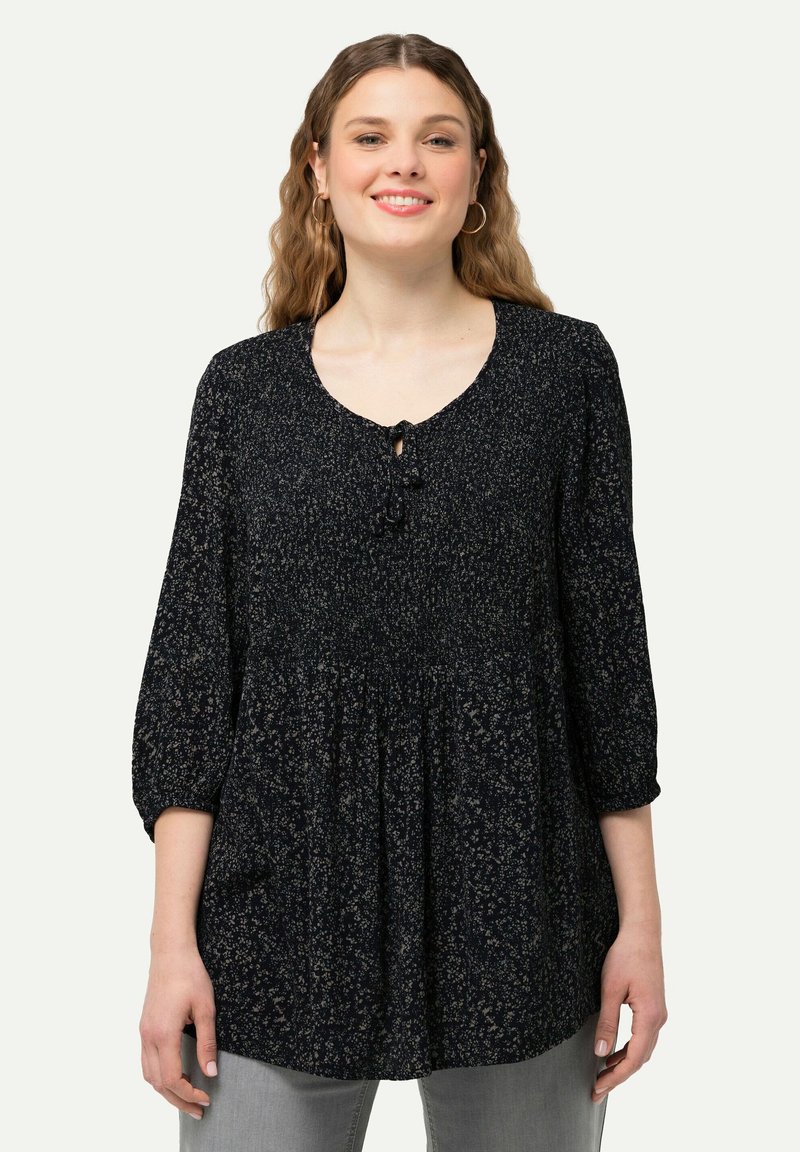 Blusa blu navy con maniche a tre quarti, scollatura rotonda, vita arricciata e motivi floreali in tonalità più chiare; include un dettaglio con bottone al collo.