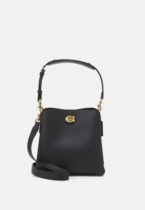 Sort lædertaske med guldfarvet drejelås, justerbar skulderrem og en ekstra aftagelig crossbody-rem på hvid baggrund.