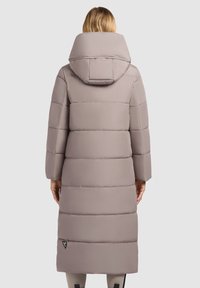 Lange, fluffige jas in lichtgrijs met een grote capuchon, ingericht met een gewatteerd ontwerp en een merklabel nabij de zoom. Heeft brede mouwen en een relaxte pasvorm.