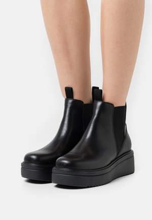 Stivali Chelsea in pelle nera con pannelli elastici ai lati, punta arrotondata e una fitta suola platform nera. Presentano linguette per una facile indossabilità.