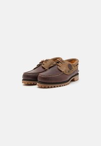 Chaussures en cuir marron avec une tige en daim beige, bout rond, couture contrastée et semelle en caoutchouc texturée présentant un motif de traction distinct.