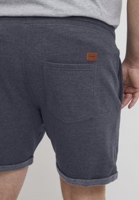 Grå bomullsblandingsshorts med rullet kant, har en baklomme og en liten lærmerkelapp i beige på midjen.