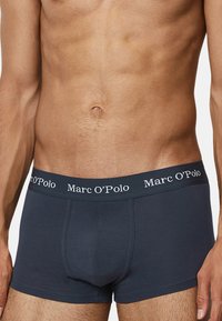 Tummansiniset boxerit pehmeästä kankaasta, jossa on brändätty joustava vyötärö, jossa lukee "Marc O'Polo." Klassinen, tiivis istuvuus saumattomalla designilla.