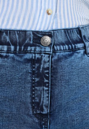 Jeans mit einer dunkelblauen Waschung, die einen silbernen Knopf, kontrastierende Nähte und eine strukturierte Oberfläche aufweist. Sichtbare Seitentasche auf der linken Seite.