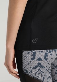 Black athletic top with a textured finish, paired with patterned leggings featuring geometric designs in shades of gray and navy.