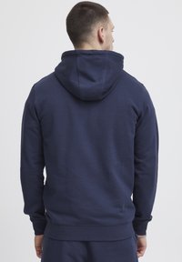 Marineblauwe hoodie van een katoenmix, met een kangoeroezak, capuchon met trekkoord en ribgebreide manchetten en onderrand, gezien vanuit de achterkant.