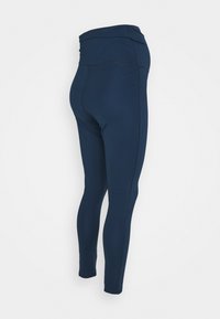 Tmavě modré legíny z elastické látky, vybavené vysokým páskem a elegantním střihem. Hladká textura bez viditelných vzorů nebo kovových doplňků.