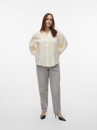 Ανοικτό κίτρινο πουκάμισο με κουμπιά, άνετη εφαρμογή και μακριά μανίκια, συνδυασμένο με γκρι τζιν με στενή γραμμή και μαύρες ψηλοτάκουνες γόβες με μυτερή μύτη.