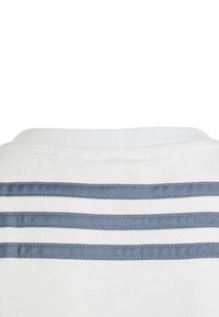 Biała koszulka z trzema poziomymi niebieskimi paskami na zapięciu z tyłu. Wykonana z gładkiego materiału, z klasycznym okrągłym dekoltem.