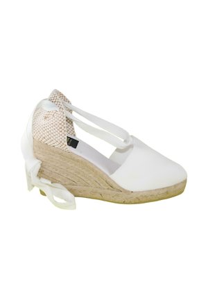 Cuña blanca de esparto con suela de yute trenzado y tiras para atar al tobillo, con contrafuerte del talón tejido en beige.