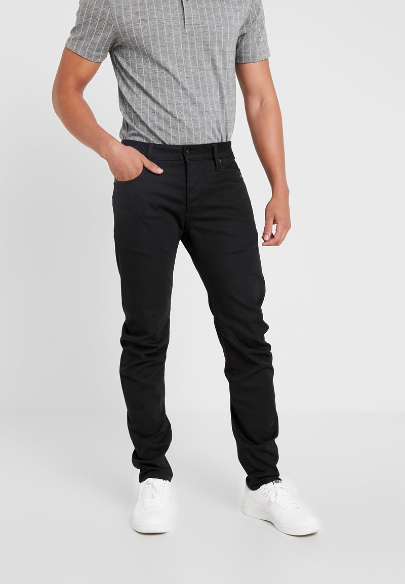 Svarta byxor i bomullsblandning med slim fit, med en klassisk femficksdesign och i kombination med en grårandig polo. Vita sneakers.