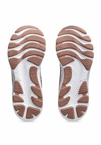 Running shoe soles with a textured rubber surface, featuring a wavy pattern in white and light brown, designed for grip and flexibility.