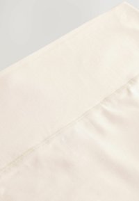 Beige stof met een gladde textuur; heeft een naad aan de bovenkant en een iets lichtere schaduw in het bovenste gedeelte.