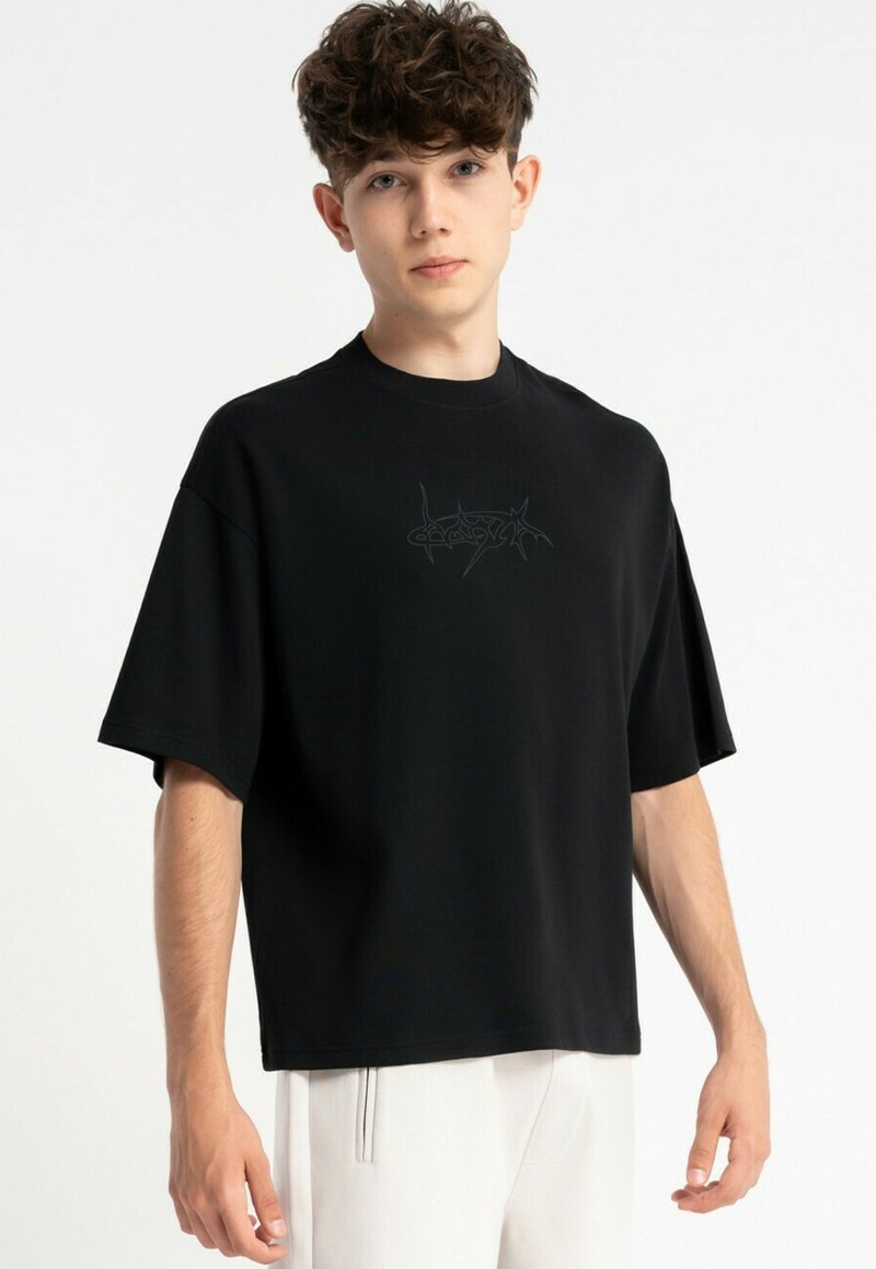 Czarna, oversize koszulka wykonana z bawełny, z okrągłym dekoltem i krótkimi rękawami, ozdobiona subtelnym graficznym logo z przodu.
