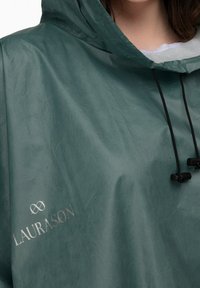 Grøn vandtæt poncho med hætte, snøre-lukninger og et sølv logo "LAURASON" på den nederste venstre side.