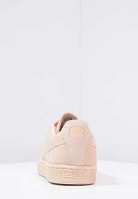 Ljusrosa mockasneaker med en strukturerad gummisula, vadderad krage och Puma-logga på hälen. Rundad form med diskret sömnad.