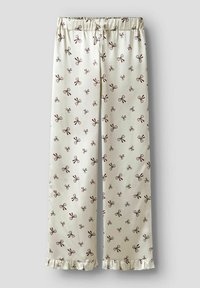 Crème-kleurige pyjamabroek met donkerbruine strikpatronen, elastische tailleband met trekkoord en ruches aan de onderkant op een lichtgrijze achtergrond.