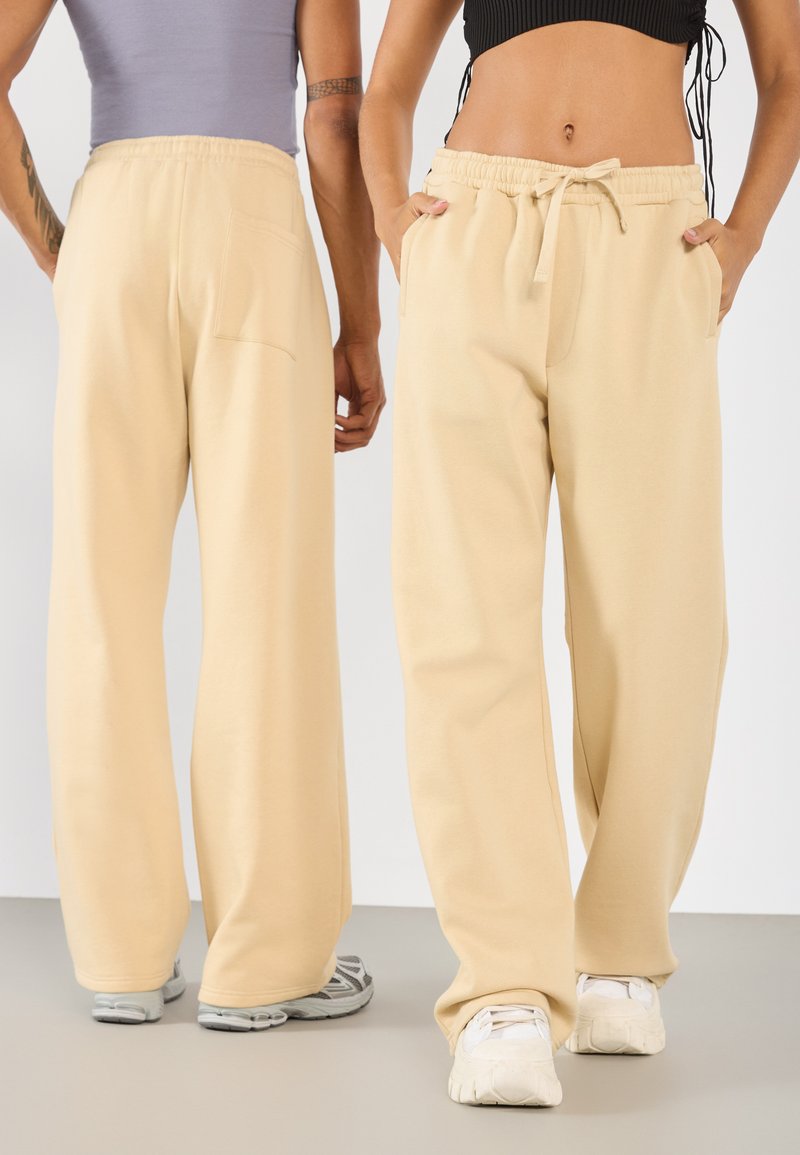 Krämfärgade, vida sweatpants med elastisk midja, sidofickor och en bakficka. Mjuk textur i en avslappnad passform.
