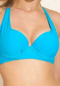 Turkusowy biustonosz bikini z formowanymi miseczkami, halterowymi ramiączkami i przeszyciami. Gładka tekstura z lekkim wypełnieniem dla wsparcia.