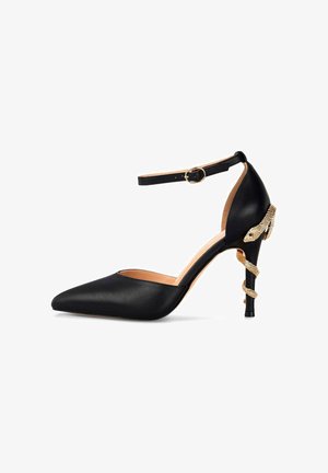 Scarpa nera in pelle con tacco alto, punta affilata e cinturino alla caviglia. Un dettaglio di serpente dorato si avvolge attorno al tacco per un tocco di design in più.