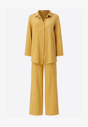Gult to-delt sæt bestående af en langærmet skjorte med knapper og bukser med vide ben, lavet af tekstureret stof med et subtilt krøllede mønster.