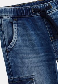 Pantaloni jogger in denim blu scuro. Caratterizzati da una cintura elasticizzata con coulisse, tasche laterali e dettagli cuciti sul tessuto.