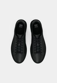 Sneakers neri con finitura in pelle liscia, pannelli laterali texturizzati, punta rotonda e lacci neri. Soletta Ortholite® per il comfort.