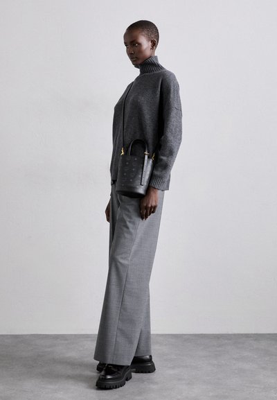 Pull à col roulé gris en maille, pantalon à carreaux large gris, sac à main noir texturé avec quincaillerie dorée, et chaussures à plateforme noires chunky.