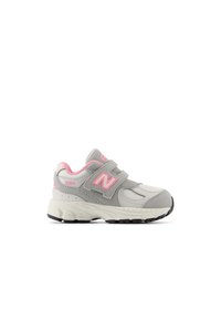 Gray athletic shoe with pink accents, featuring a velcro strap, textured materials, and a thick rubber sole with a patterned tread.