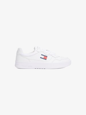 Sneaker bianca con tomaia in pelle liscia, chiusura con lacci, colletto imbottito e suola in gomma. Presenta un logo "TOMMY JEANS" rosso e blu sul lato.