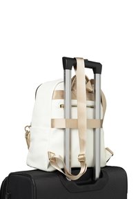 White textured backpack with gold accents secured to a black wheeled suitcase, featuring silver telescopic handle and beige straps.