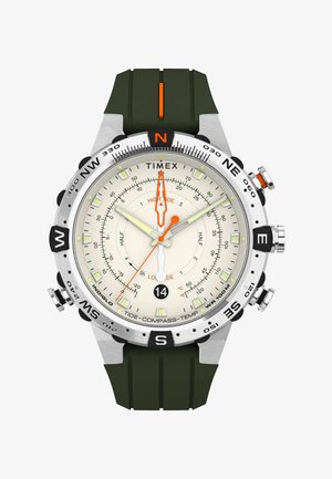 Reloj de pulsera Timex con esfera blanca, manecillas naranjas y blancas, marcas de brújula en el bisel, correa de goma negra y funciones de marea, brújula y temperatura.