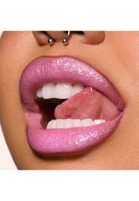 Nærbillede af læber dækket af glinsende pink læbestift, med fyldig form, glat tekstur og klare hvide tænder delvist synlige.