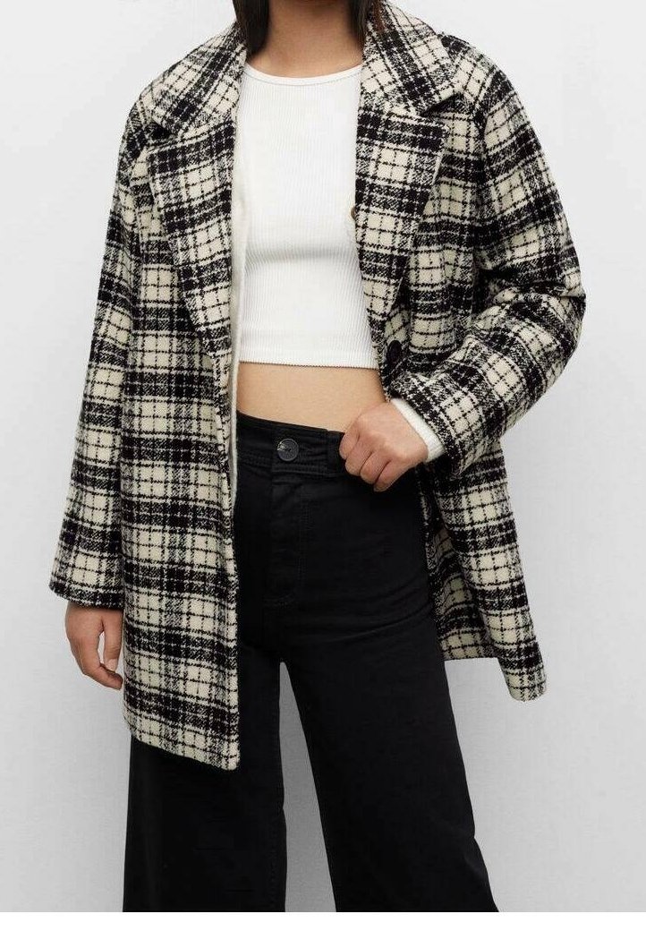 Manteau en mélange de laine à carreaux noir et blanc avec un grand col et une ouverture frontale, présentant des manches longues et une coupe décontractée.