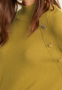 Pullover verde oliva con scollatura a coste, dotato di bottoni decorativi sulla spalla e una morbida texture lavorata a maglia.