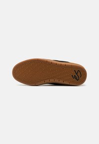 Talpa de adidași negri cu un model detaliat în fir de pește. Prezintă o talpă din cauciuc de culoare caramel, oferind un contrast de culoare și textură.