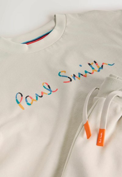 Lysebeige sweatshirt med flerfarvet "Paul Smith"-skrift over brystet og matchende joggingbukser med hvide snore og orange ender.